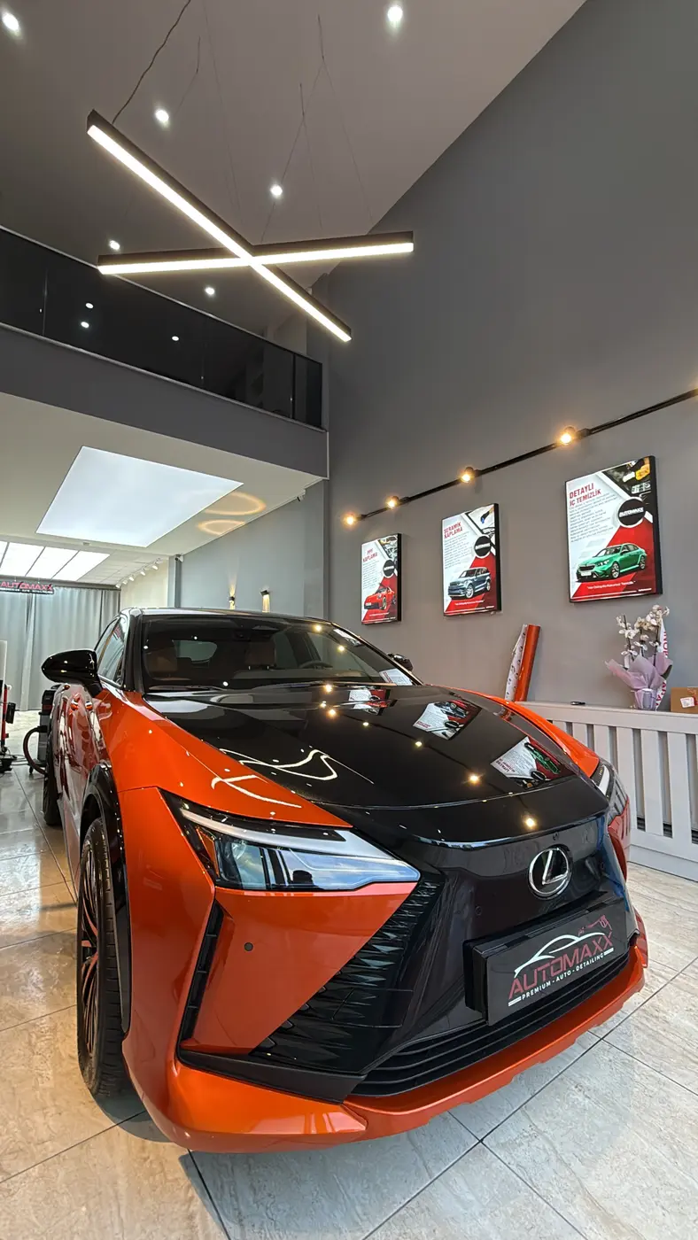 Automaxx showroomunda turuncu gövdeli araç ve duvardaki hizmet panoları